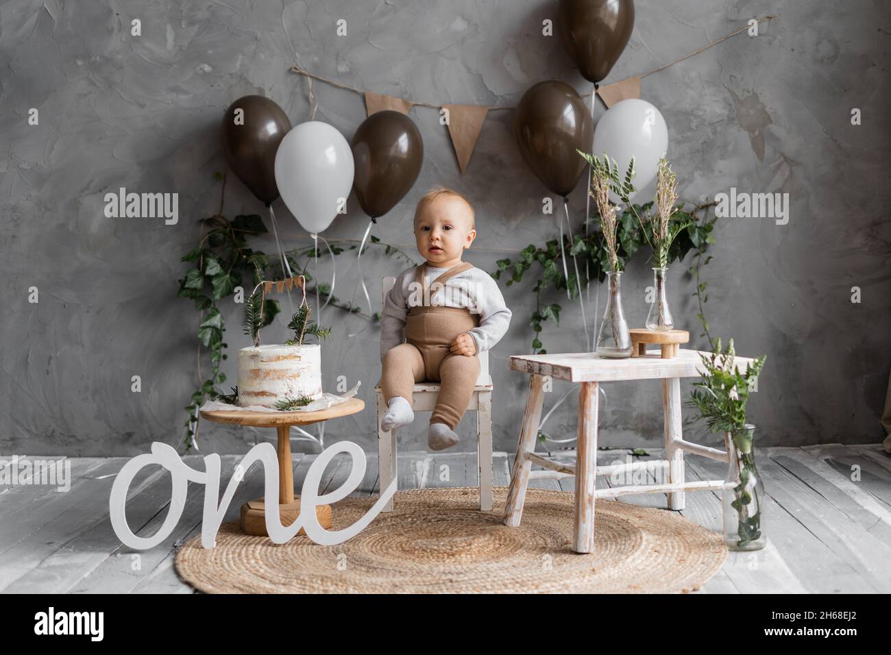baby's birthday, natural decor for the first year, baby on the background of balloons and cake, rustic style decoration, happy baby one year holiday. Stock Photo