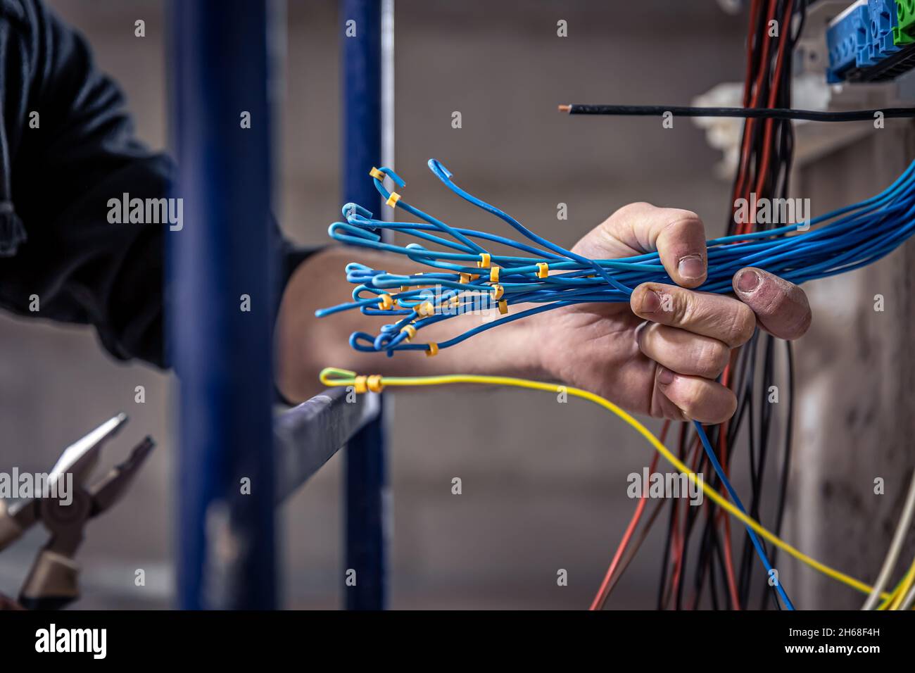 A male electrician works in a switchboard with an electrical connecting cable. Stock Photo