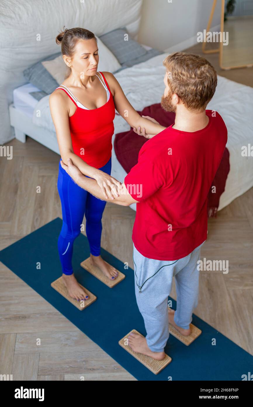 Couple standing on Sahu boards with sharp nails - man supporting his wife. Yoga practice together. Stock Photo