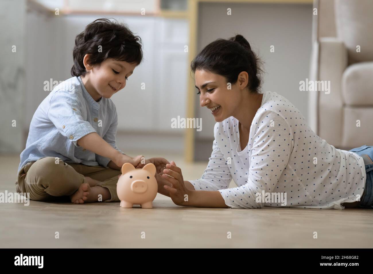 Happy Indian kid and young mom saving money together Stock Photo