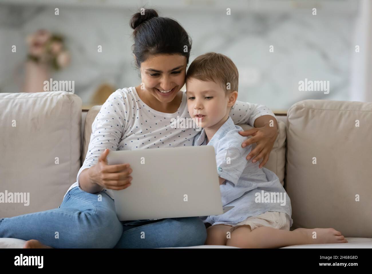 Curious kid and happy nanny holding laptop Stock Photo