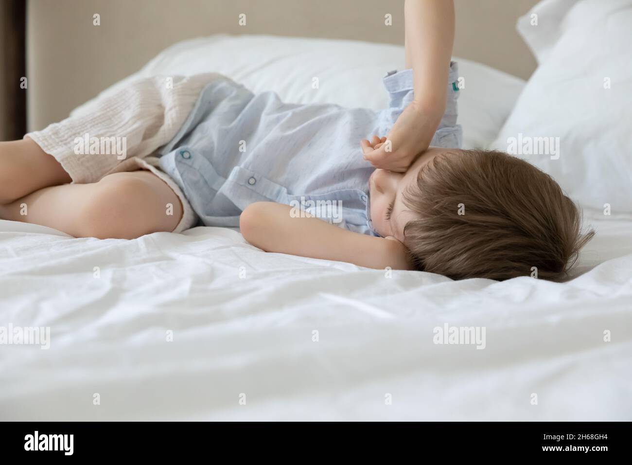 Sleepy preschool kid resting in bed, sleeping in daytime Stock Photo