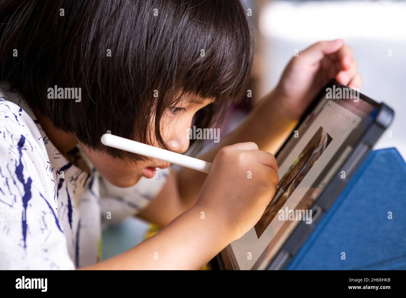 little girl using a digital pen and drawing on tablet touch screen pad with digital pencil to be creative and to make digital art and learning in home Stock Photo