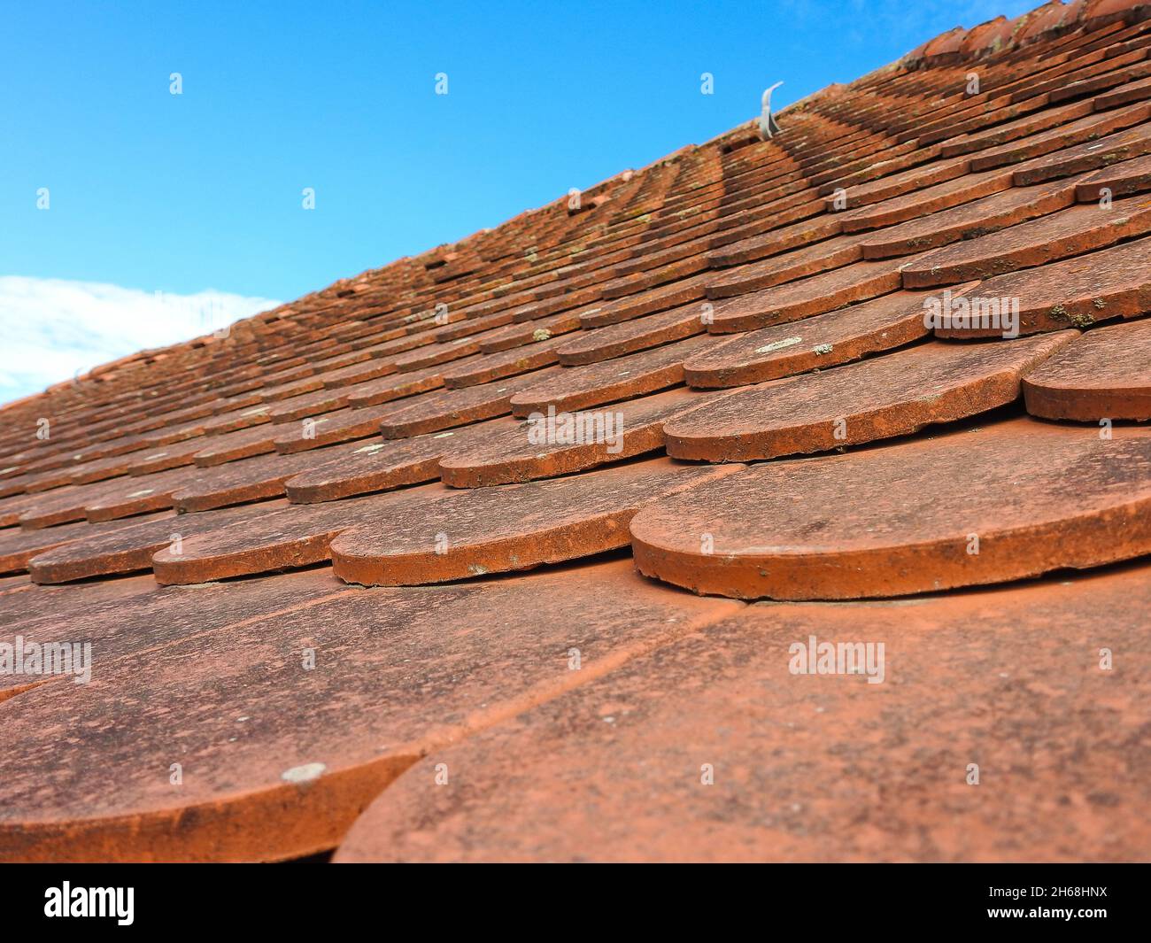 A closeup shot of old red roof tiles against blue sky Stock Photo