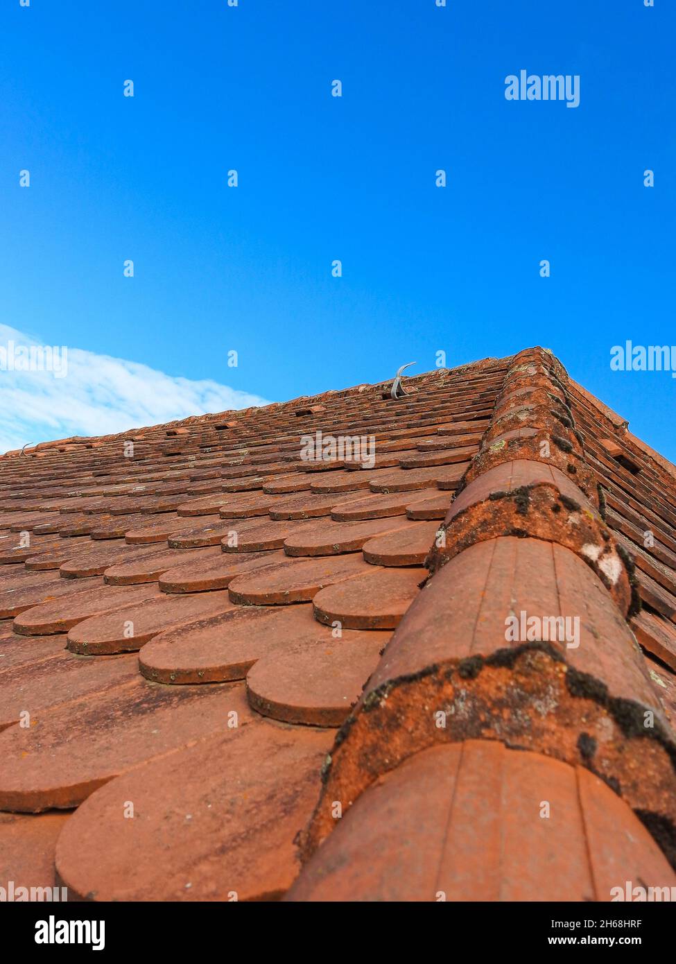 A vertical shot of old rusty roof tiles against blue sky Stock Photo