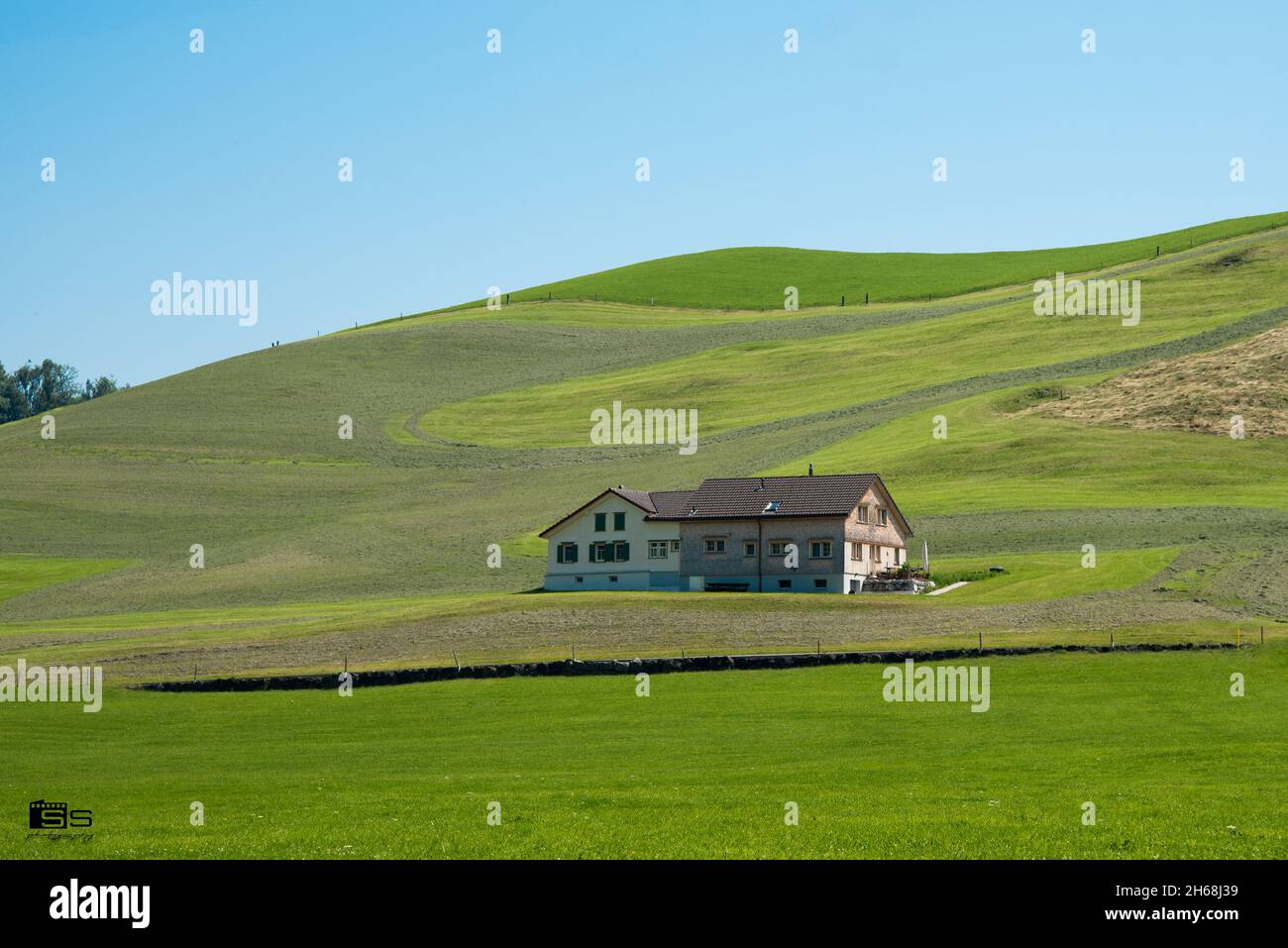 A single house in the middle of a wide grassy field on a hill Stock ...