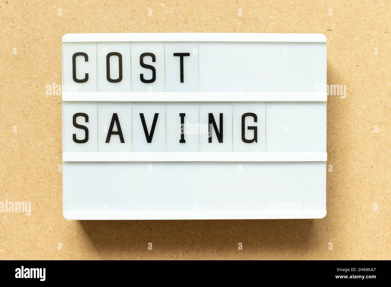 Lightbox with word cost saving on wood background Stock Photo