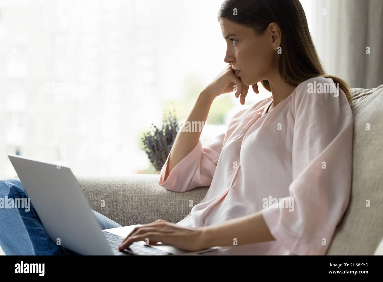 Pensive young woman thinking on problem solution, working on computer. Stock Photo