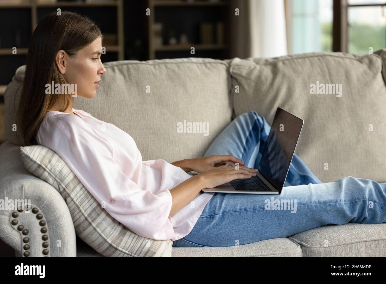 Relaxed happy young woman using computer at home. Stock Photo