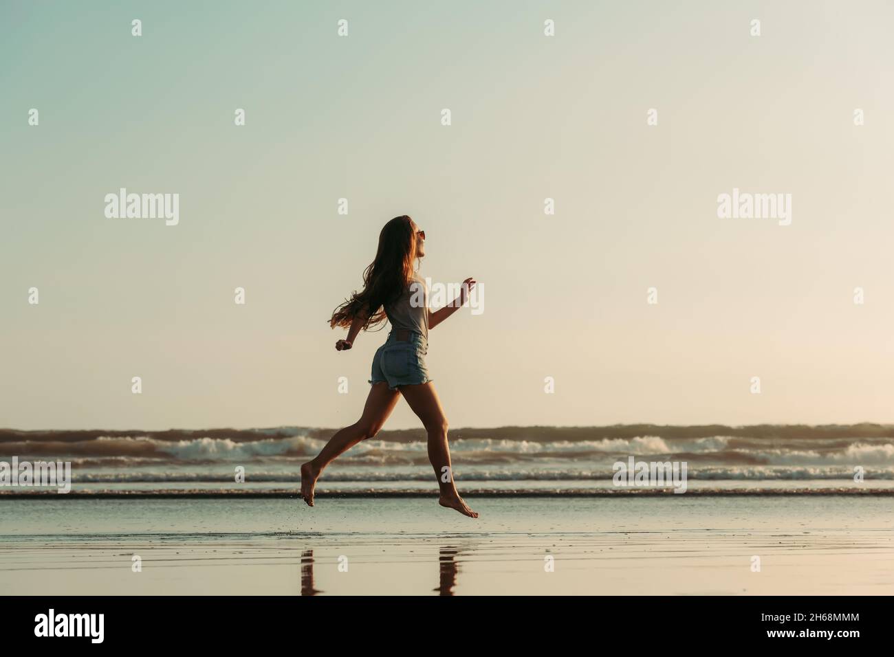 Happy beautiful girl walks or runs at sunset sea or ocean beach at Bali island Stock Photo
