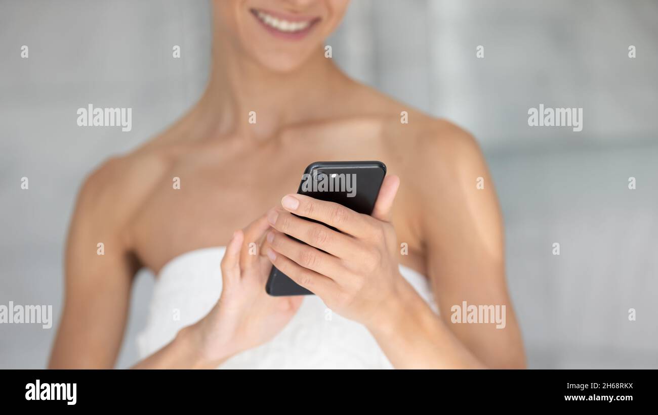 Young mixed race woman using cellphone after shower. Stock Photo