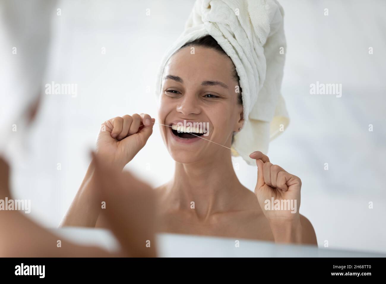 Happy beautiful young hispanic woman cleaning teeth with dental floss