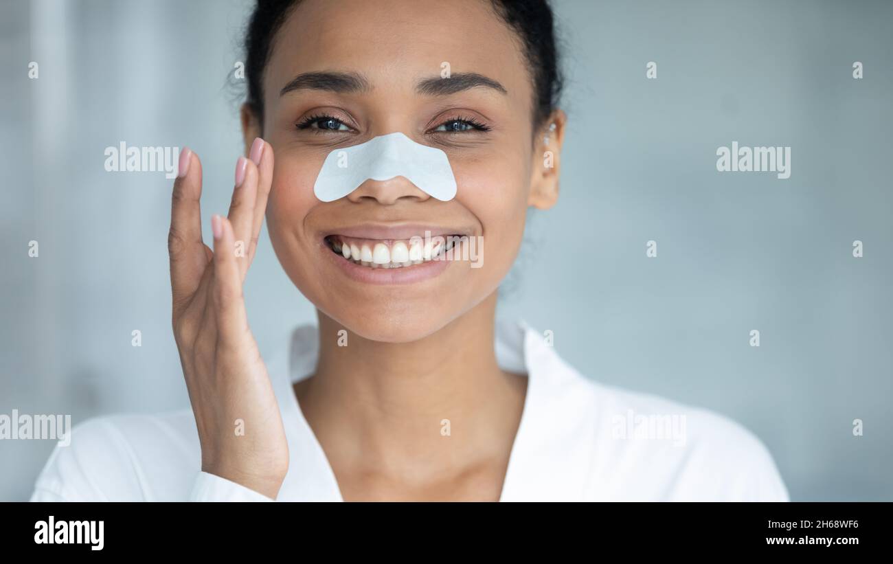 Happy beautiful african ethnicity woman using nose cleansing strip. Stock Photo