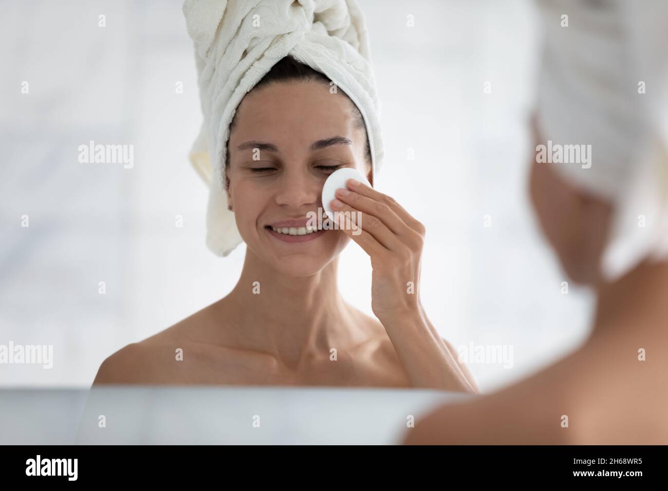 Happy hispanic woman cleaning face with cotton pad. Stock Photo