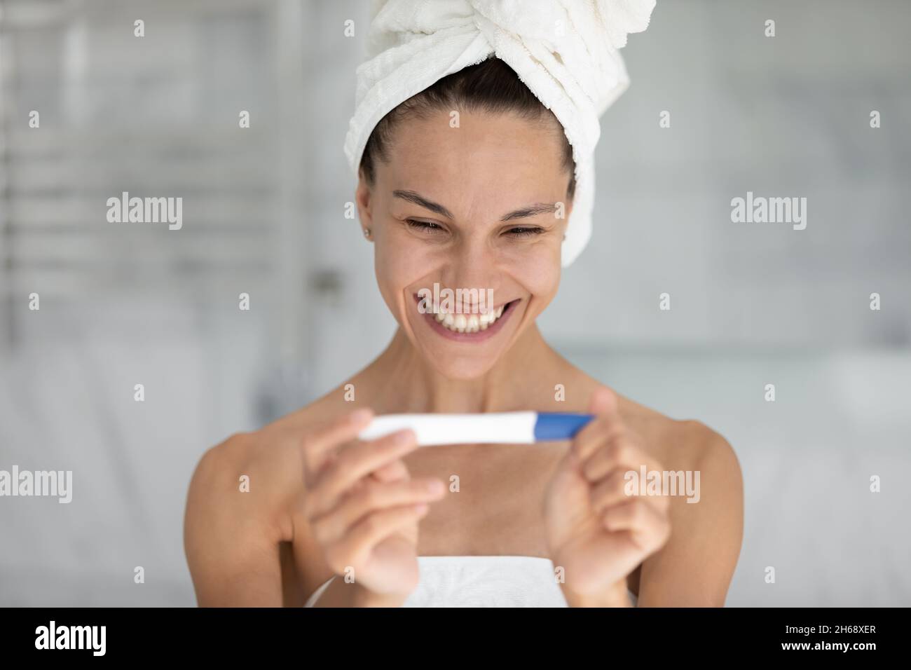 Happy beautiful young mixed race woman looking at pregnancy test Stock