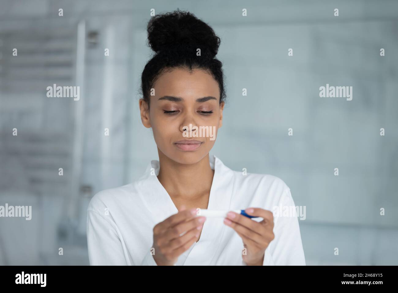 Concentrated young african mixed race woman using pregnancy test Stock