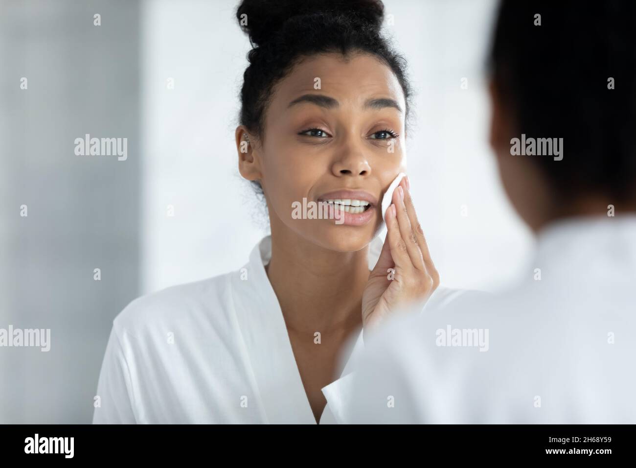 Happy african american woman applying toner with cotton pad. Stock Photo