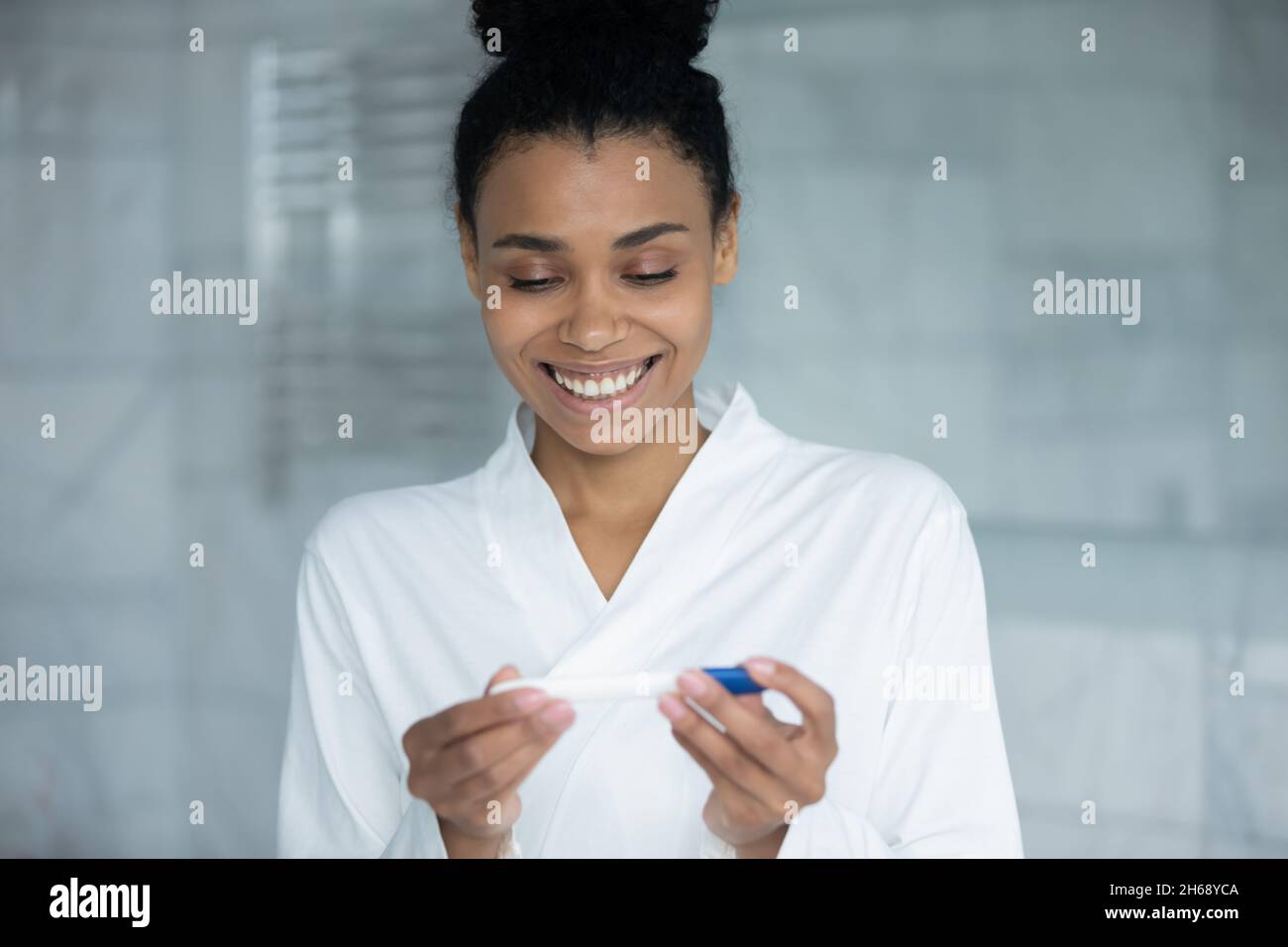 Happy interested young african mixed race woman using pregnancy test