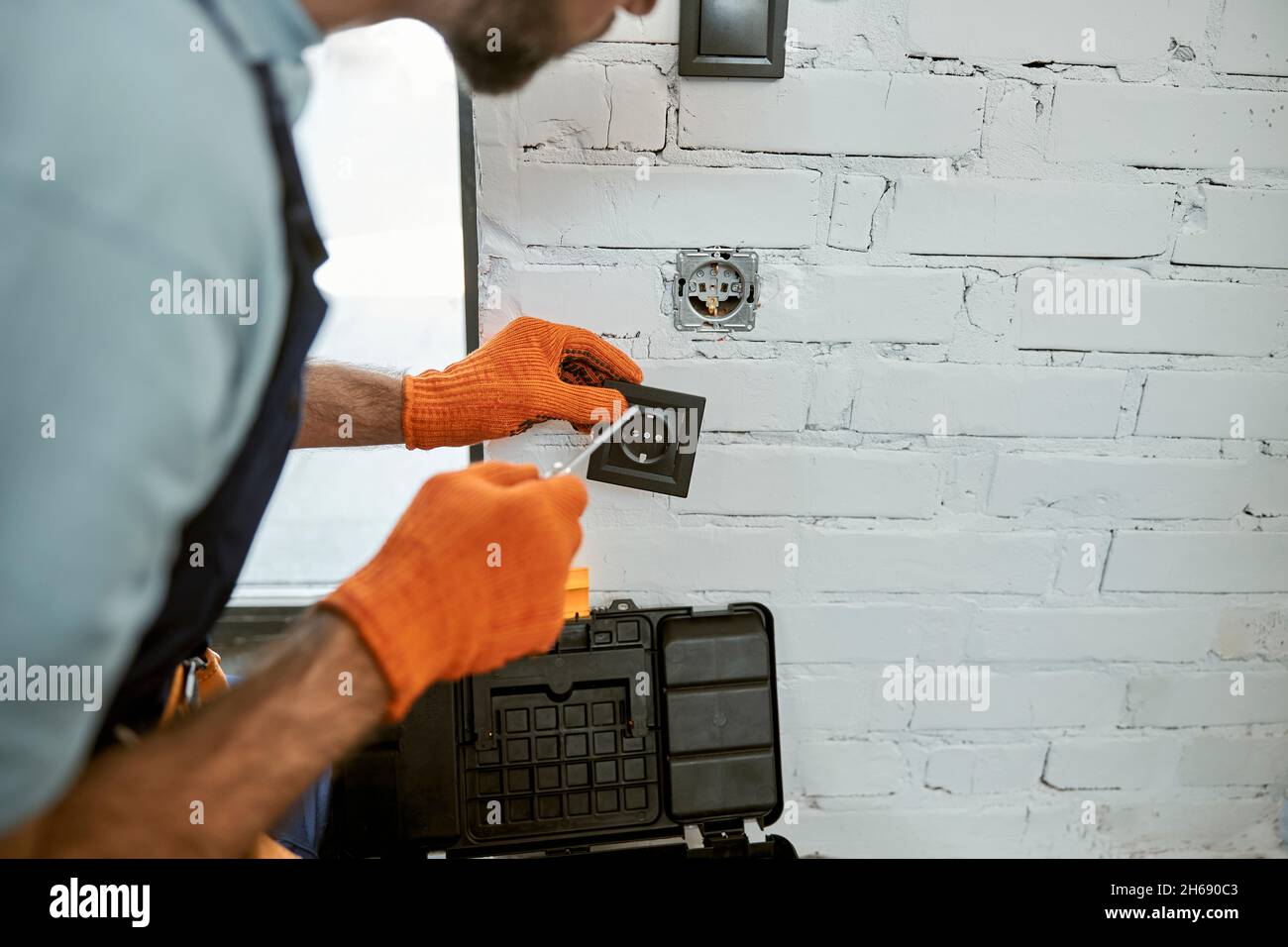 Man hands fixing electrical wall socket with screwdriver Stock Photo
