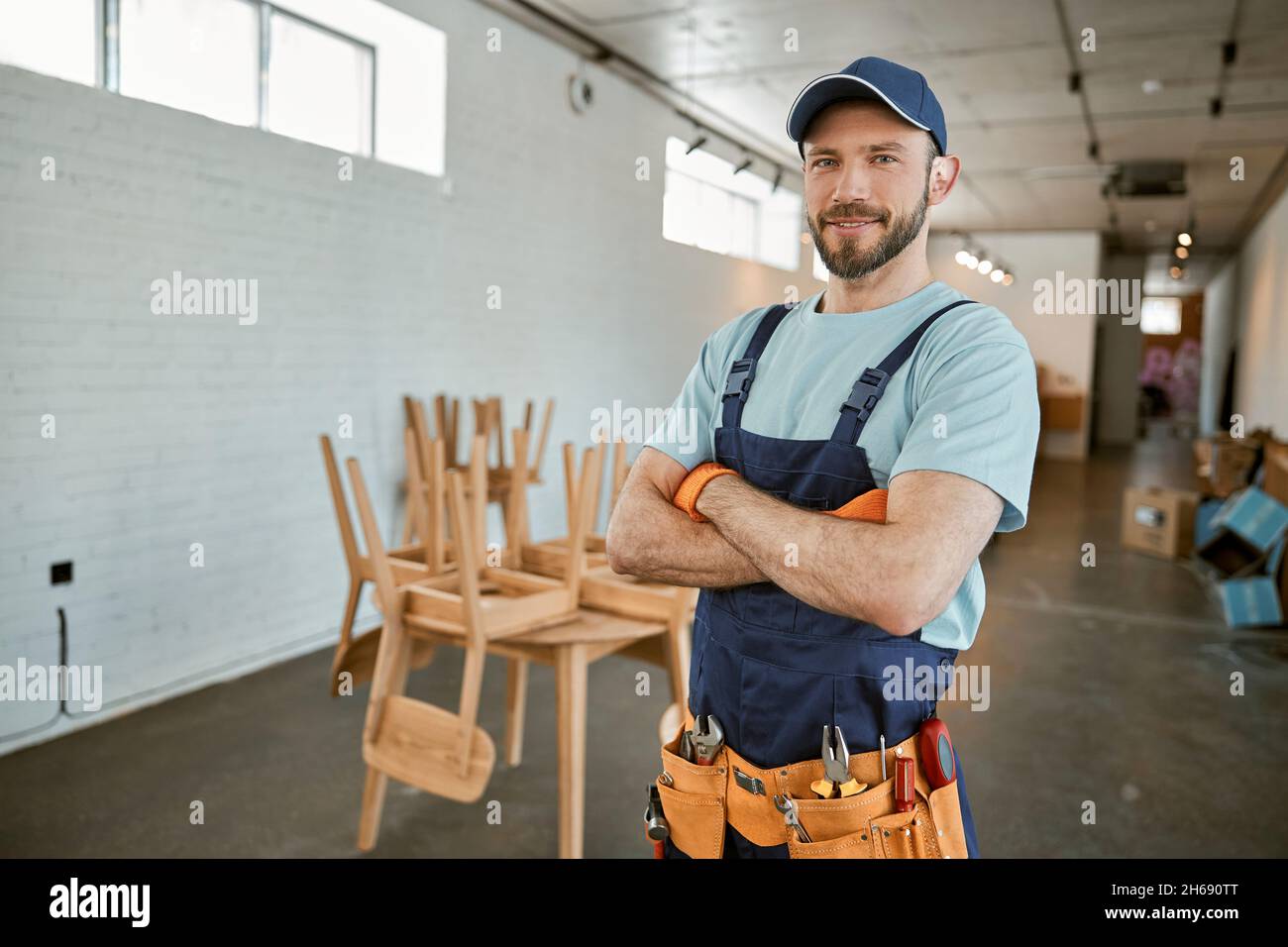 Cheerful male worker in cap standing in workshop Stock Photo