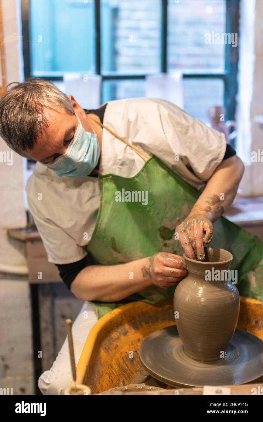 skilled worker demonstrates throwing a ceramic vase from clay on a