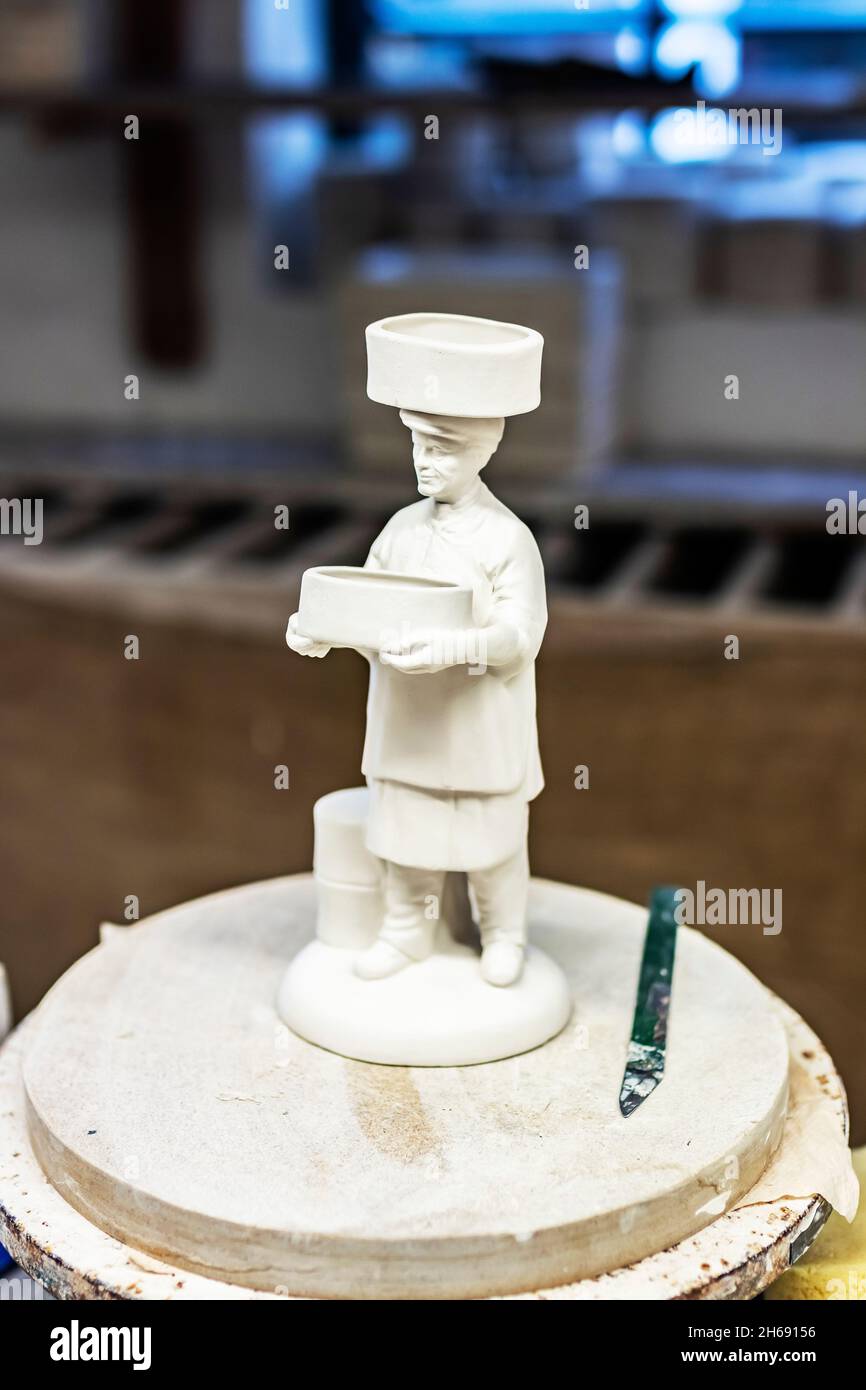 unglazed ceramic clay model of pottery worker with sager on head at