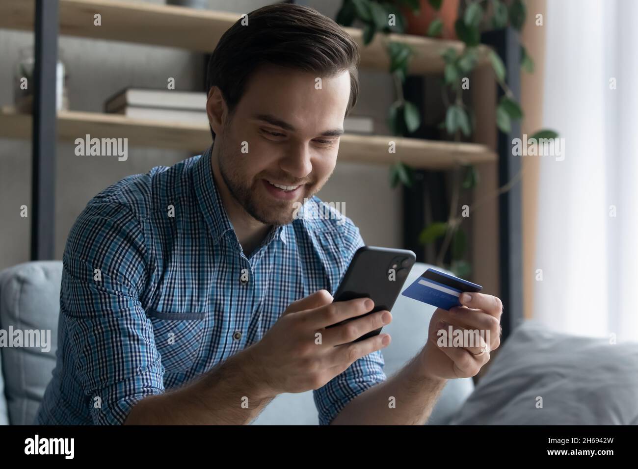 Happy young man shopping using mobile application. Stock Photo