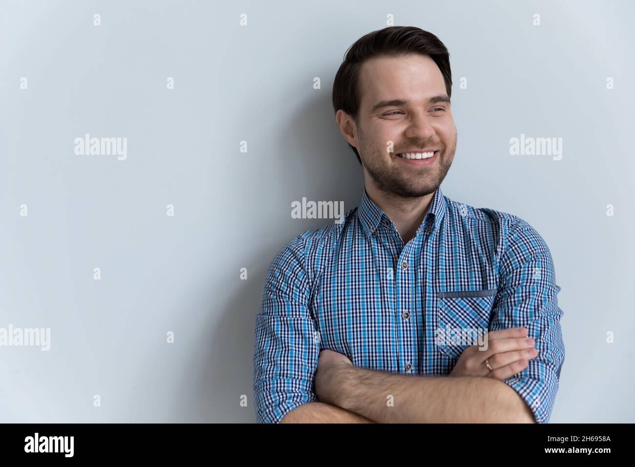 Smiling young man looking in distance posing on white studio background. Stock Photo