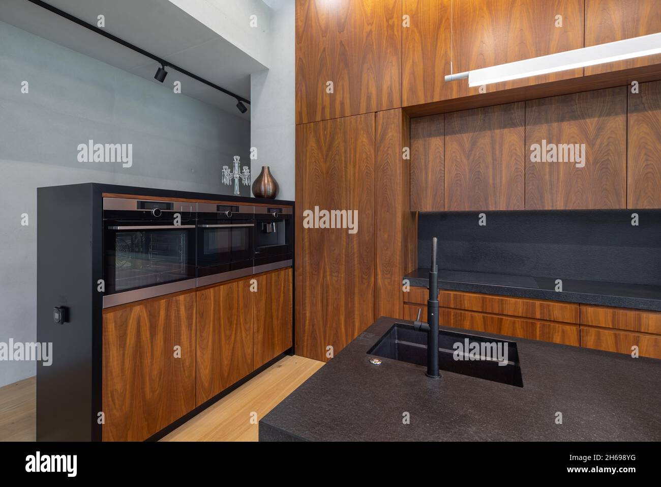 Modern interior of wooden kitchen with sink and black counter. Builtin