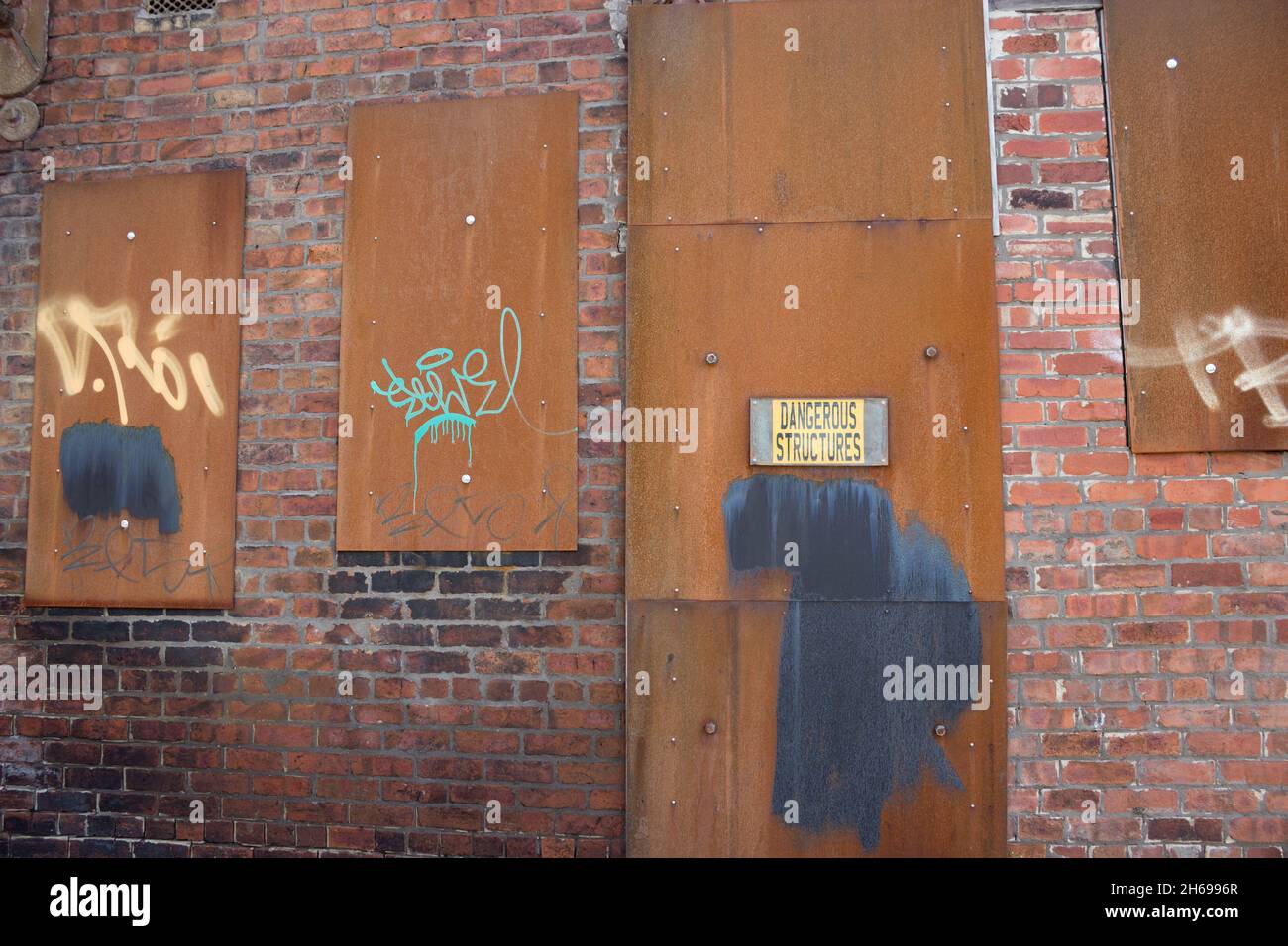 Abandoned Building, Derelict, Deserted, Sealed Off, Metal Boarded Up Windows, Rundown Urban Area, Brick Exterior In Ruins Unoccupied Location Graffiti Stock Photo