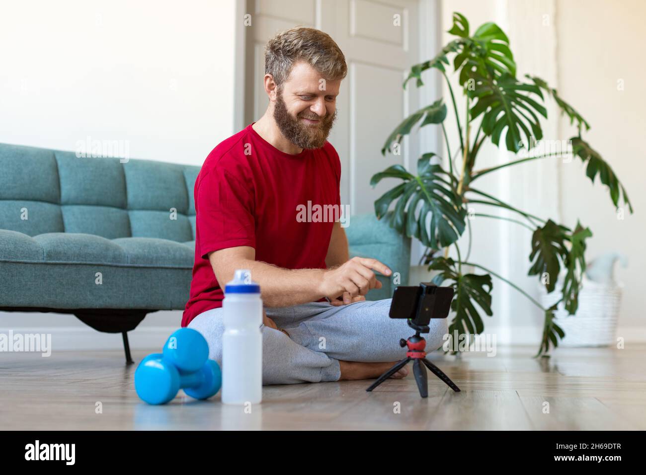 Helathy lifestyle concept - middle-aged man searches the internet for an online home workout guide. Stock Photo