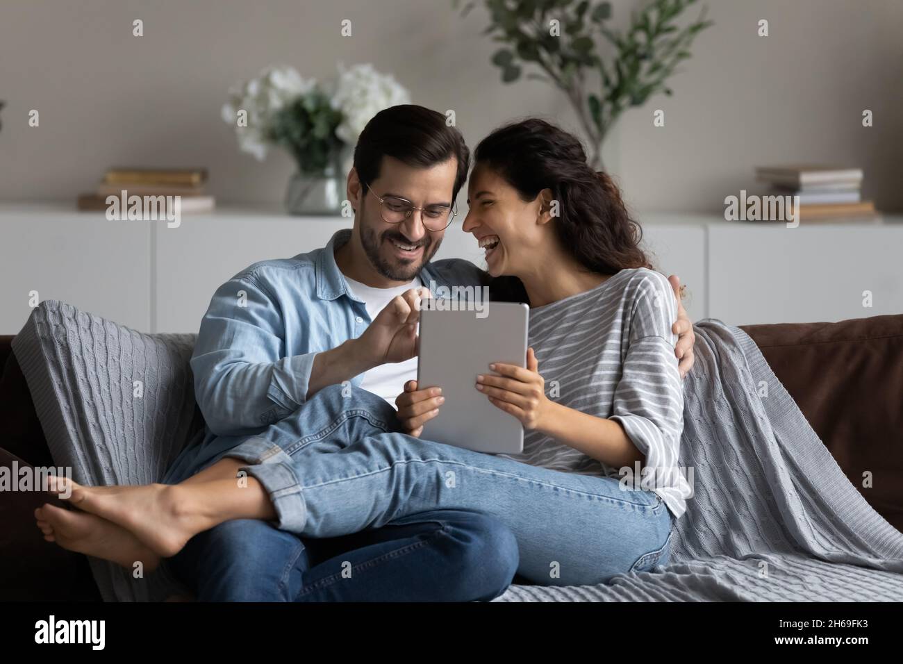 Happy laughing couple having fun with tablet at home together Stock Photo