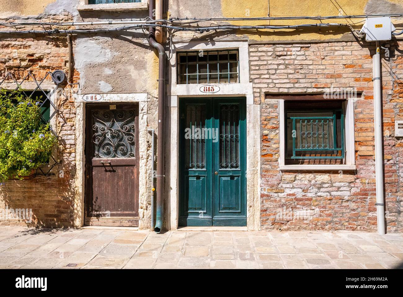Closed doors of old weathered brick wall residential houses Stock Photo