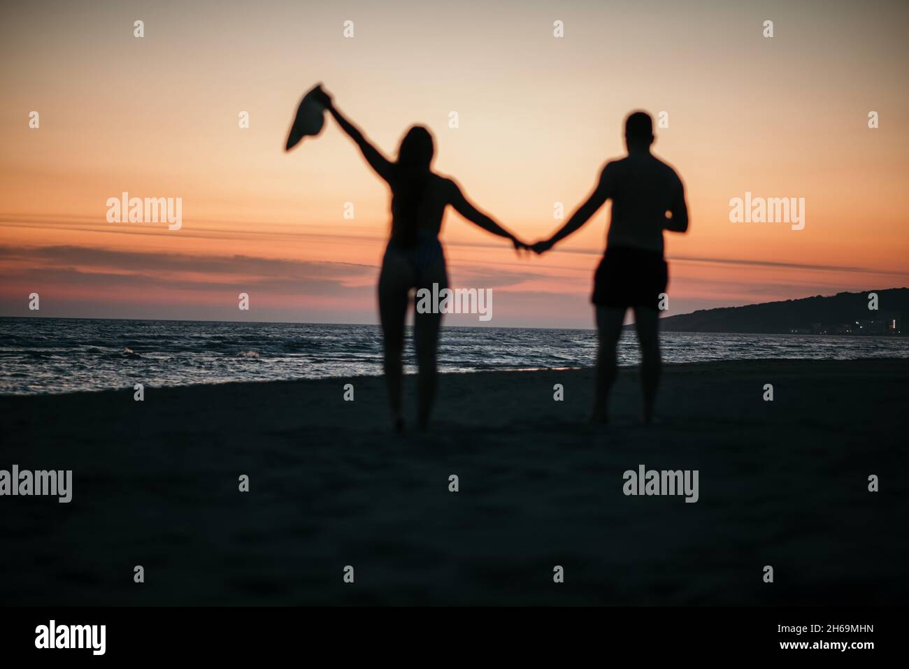 A silhouette of a romantic couple enjoying the beautiful sunset on a ...