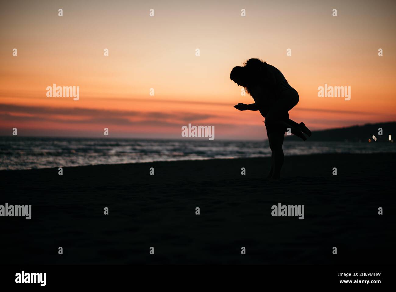 A silhouette of a romantic couple enjoying the beautiful sunset on a ...