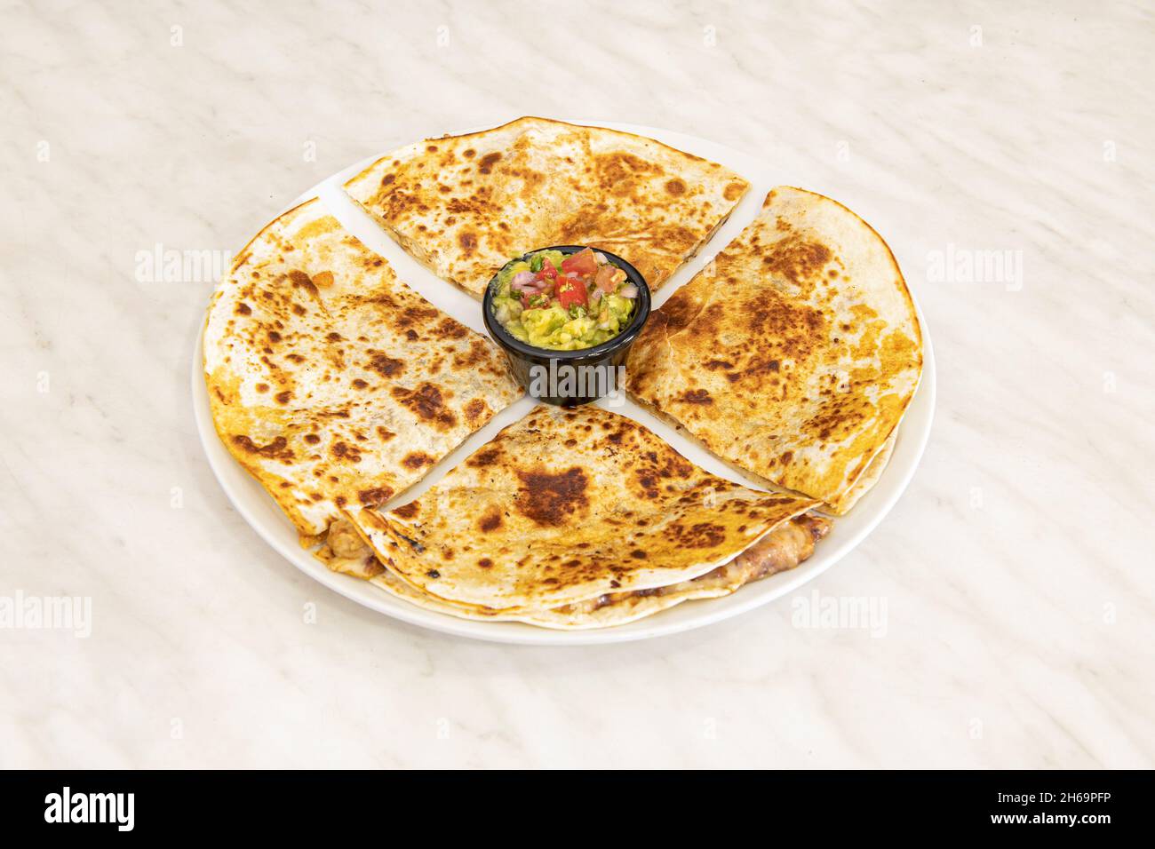 The quesadilla consists of a corn or wheat tortilla, folded in half that can be filled with cheese, beans and chicken and eaten hot, either fried or c Stock Photo