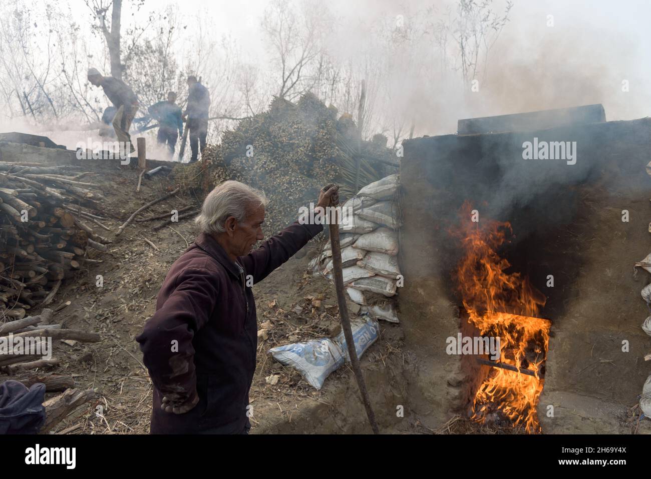 A man looks at the firewood which is used to boil wicker sticks during ...