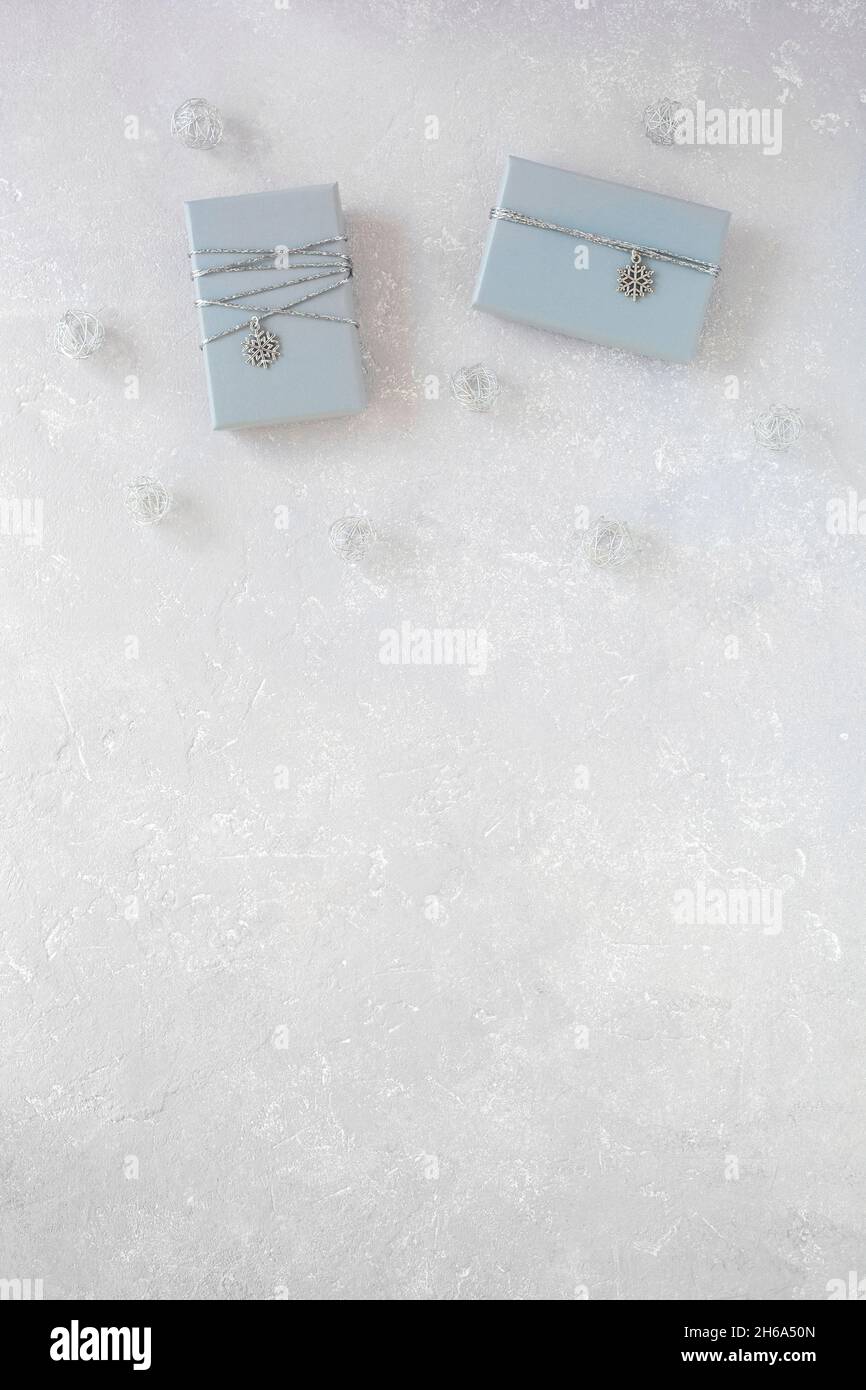 two grey gift boxes decorated with silver ribbon and snowflake pendant, on grey background, top view, copy space Stock Photo