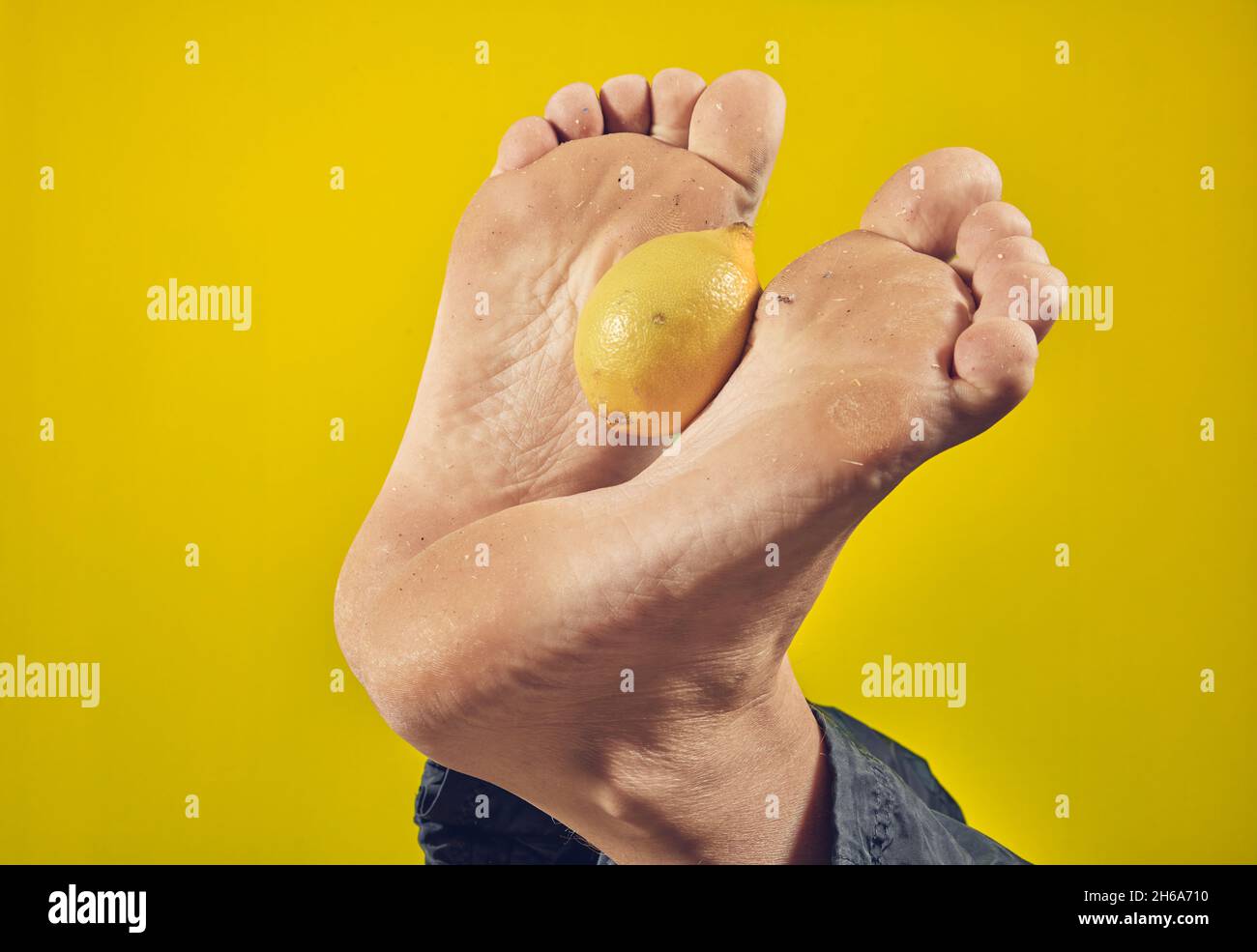 Man holding lemon with his feet Stock Photo