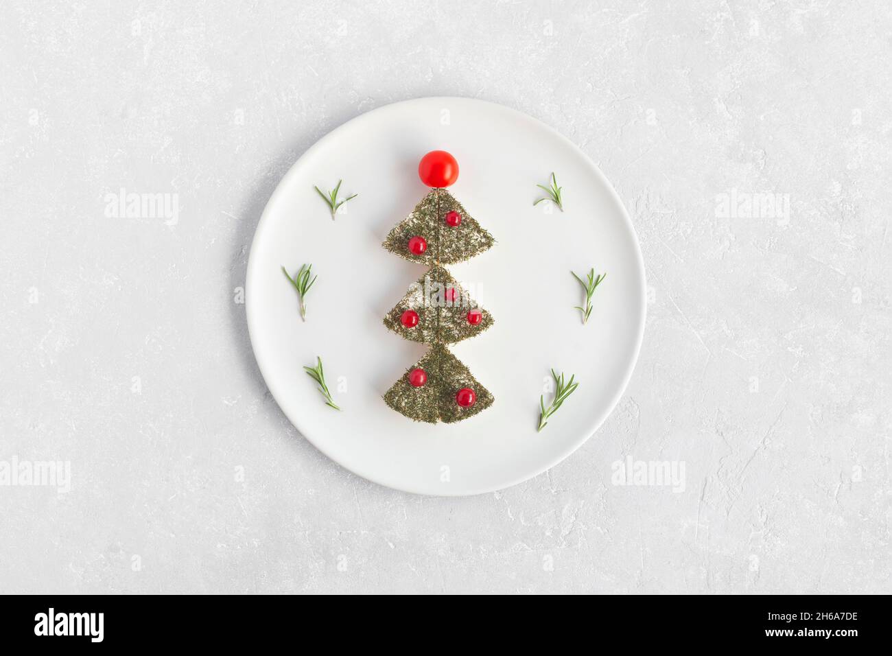 new year tree made of cheese and decorated with red currant and cherry tomatoes, decoration for new year table, white plate, top view Stock Photo