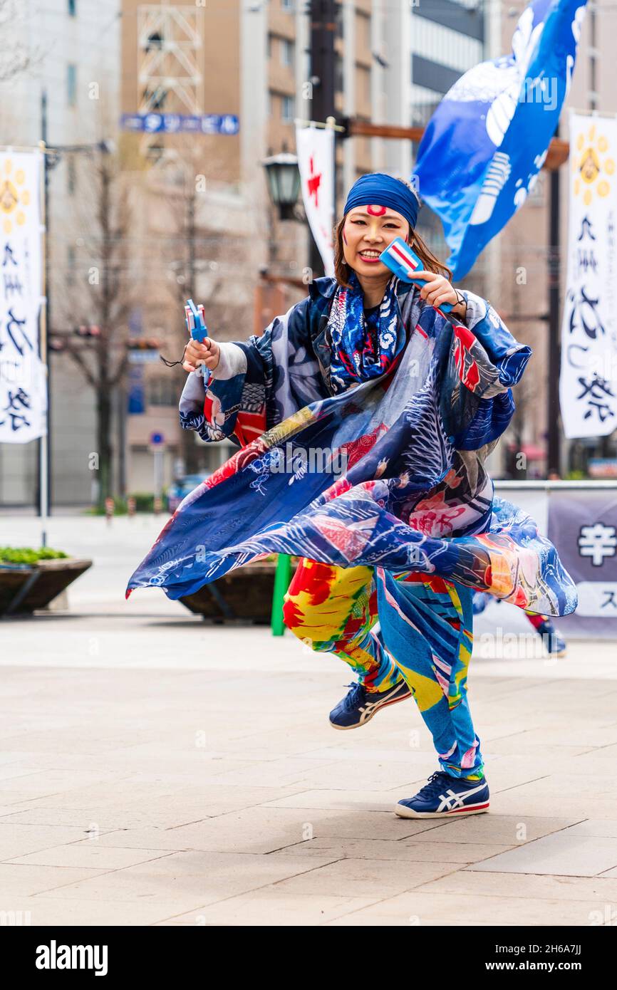 Woman Yosakoi dancer holding naruko, wooden clappers, while dancing on the pavement in Kumamoto during the Kyusyu Gassai festival. Stock Photo
