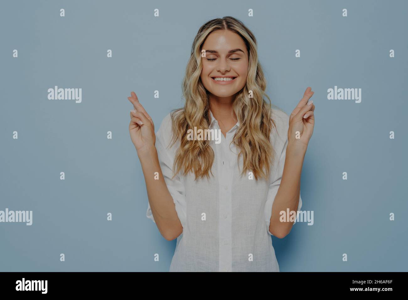 Blonde woman with closed eyes making wish Stock Photo