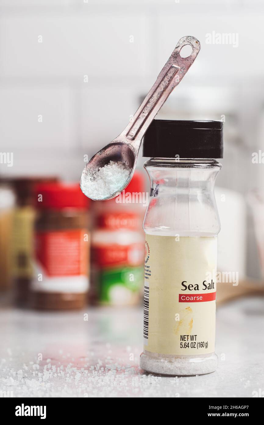 Teaspoon with Sea Salt Balances on the lid of its container in