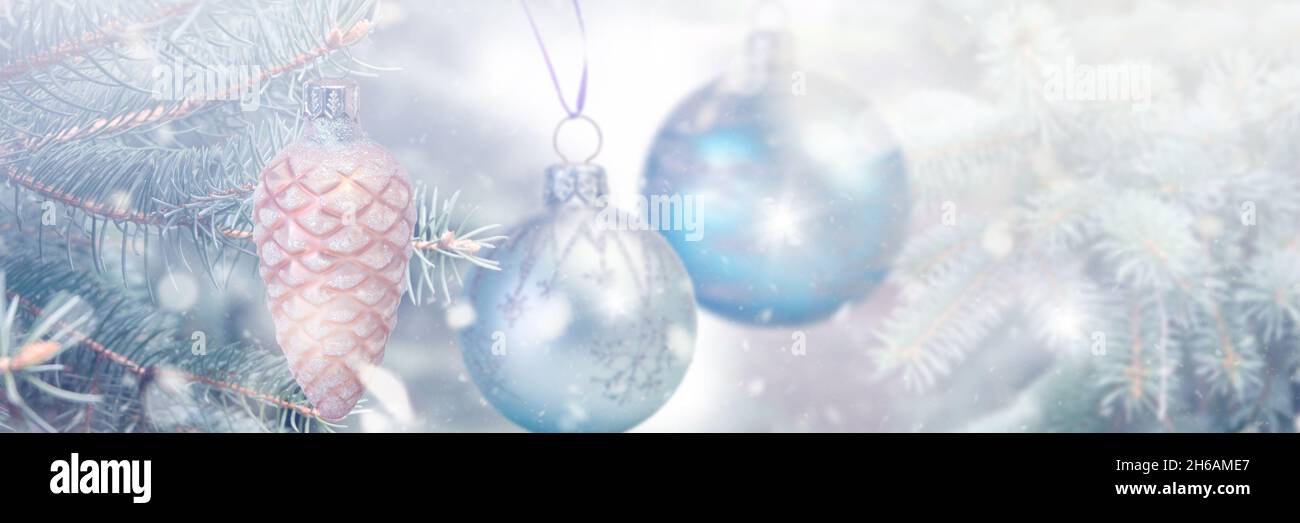 christmas tree toys on abstract defocused light blue background with fir Branches and snowfall. Winter season banner. Stock Photo
