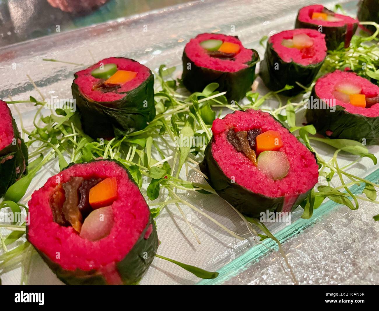Close up of colorful vegetable maki, carrot, asparagus, beetroot, seaweed on glass plate. Stock Photo