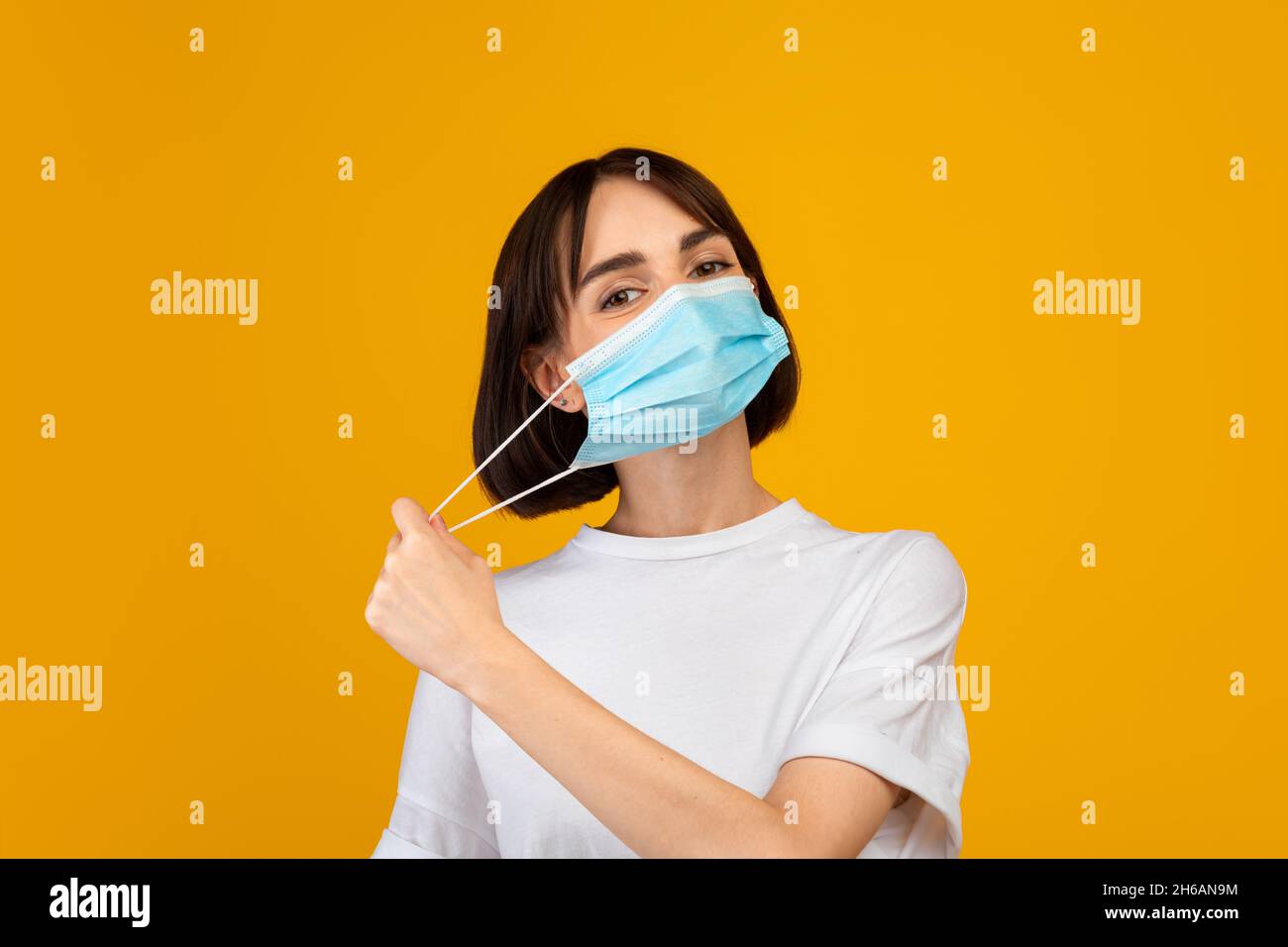 End of the epidemic. Young lady taking off protective face mask ...