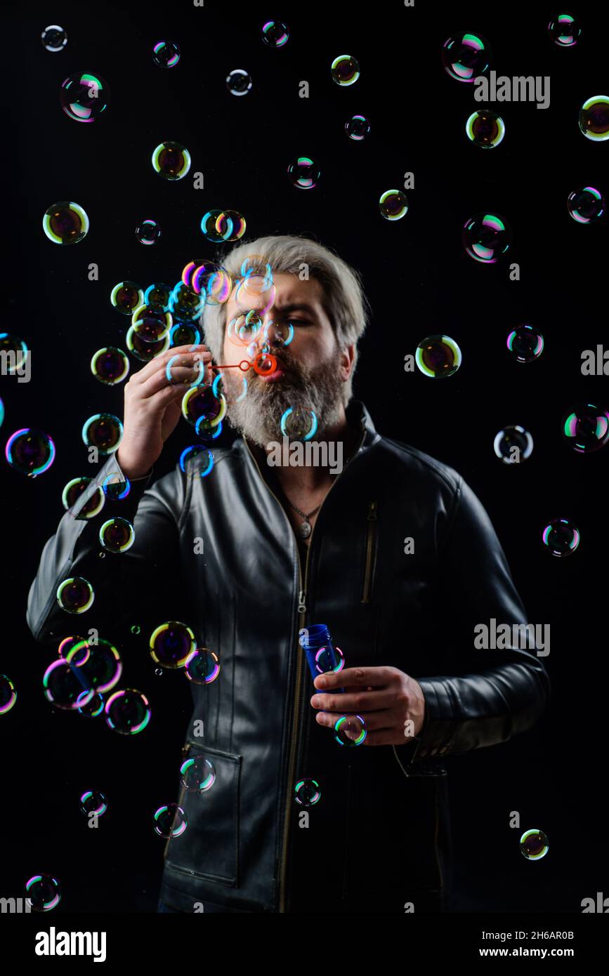 Bearded man blowing Soap bubbles. Play with inflate bubbles. Happiness. Good mood. Childhood. Stock Photo