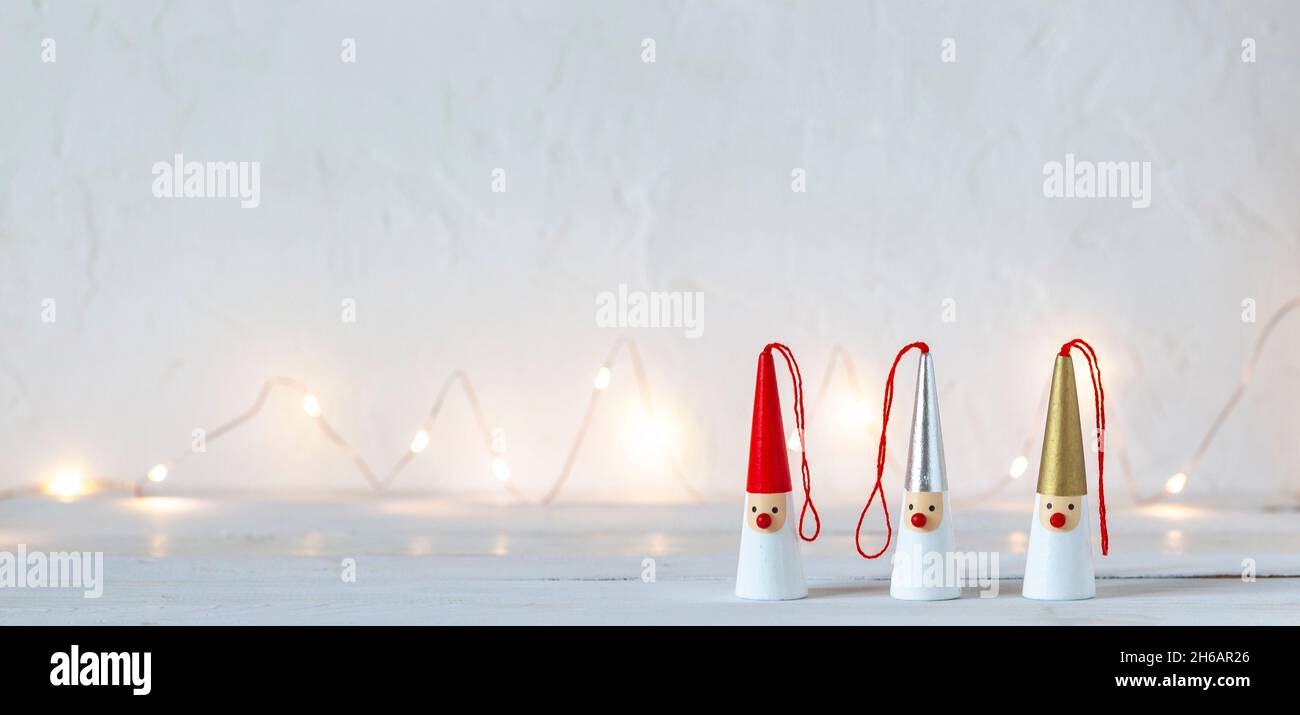 three Santa Clauses figurines on a white background, garland lights, side view, copy space Stock Photo