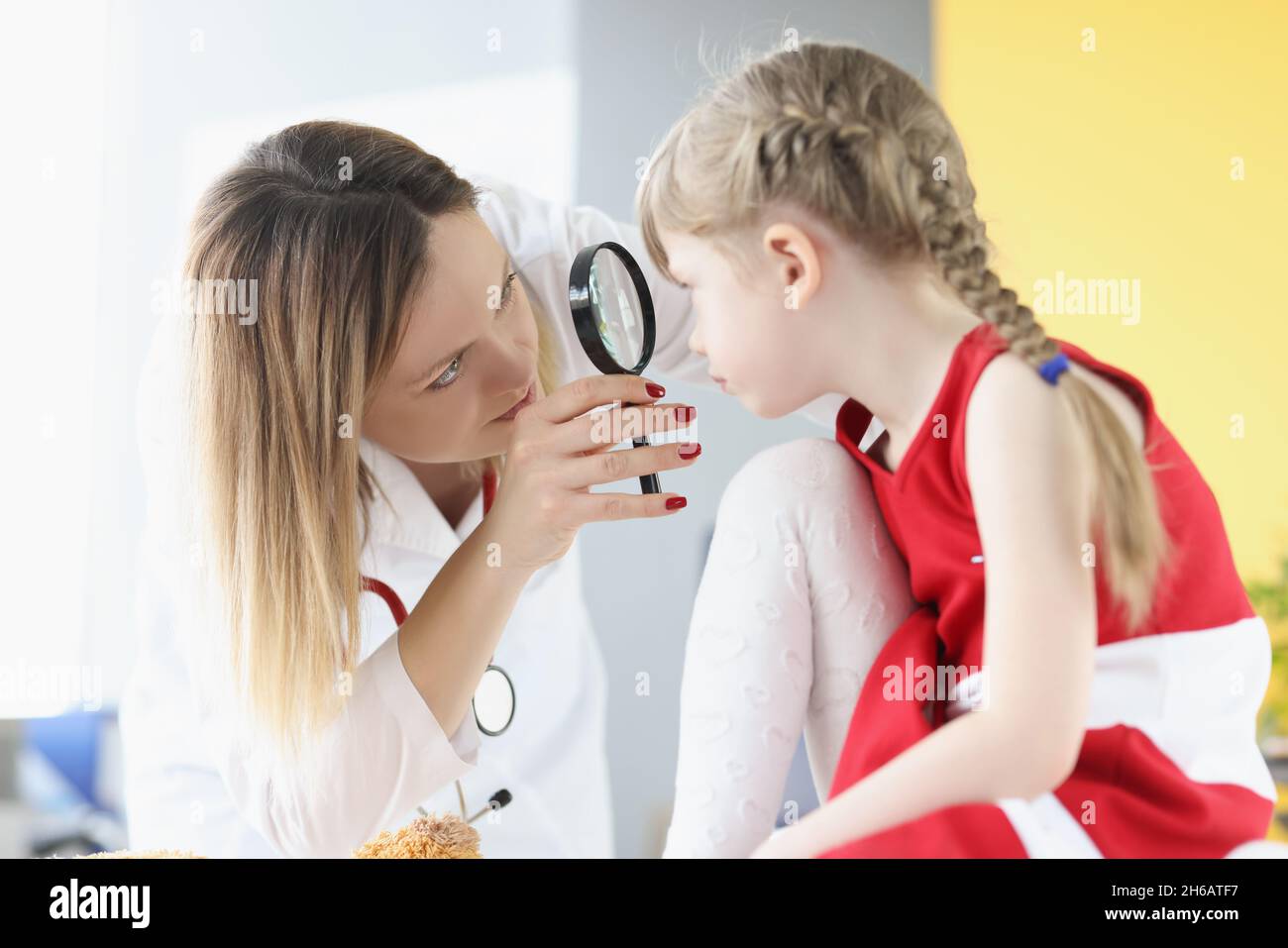 Ophthalmologist conducts medical examination of girl eye through magnifying glass Stock Photo