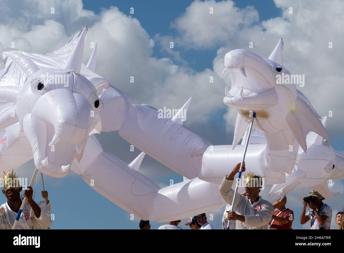 Two masked men holding white dragon at Corralejo International Kite Festival, november 2021. Fuerteventura, Spain Stock Photo
